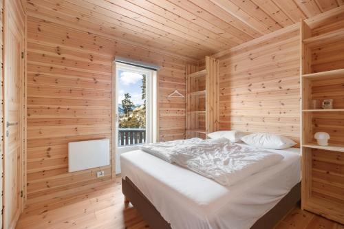 uma cama num quarto de madeira com uma janela em Een gezellig huis in Vrådal met adembenemend uitzicht em Vradal