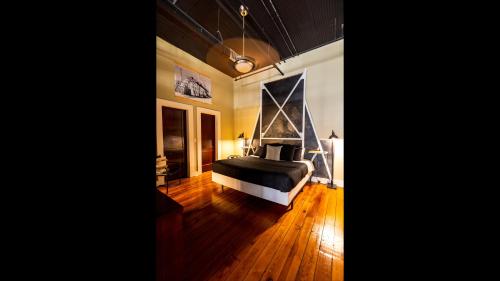 1 dormitorio con 1 cama en una habitación con suelo de madera en The C-Street Archive en Springfield