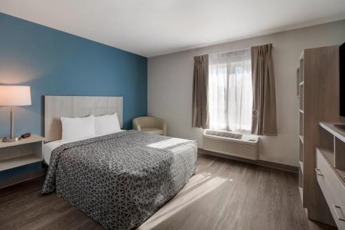 a hotel room with a bed and a window at WoodSpring Suites Detroit Sterling Heights in Sterling Heights
