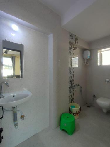 a white bathroom with a sink and a mirror at Vividora in Nagpur