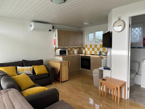 a living room with a couch and a kitchen at The Chalet in Stalham