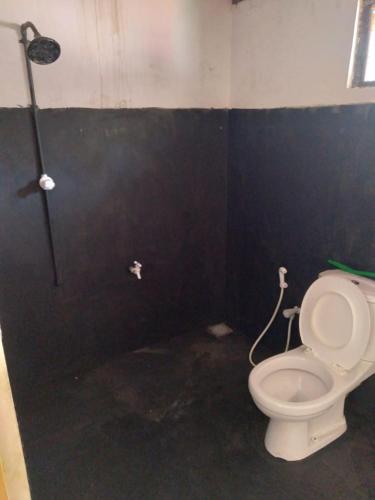 La salle de bains est pourvue de toilettes et d'un mur noir. dans l'établissement SENN Homestay, à Polonnâruvâ