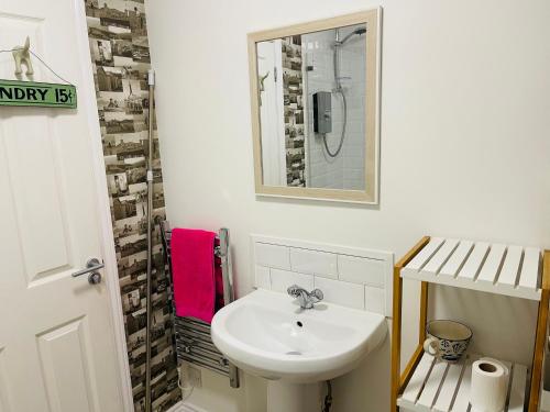 a white bathroom with a sink and a mirror at Our Happy Place- 2 bedroom apartment with designated parking - Brixham in Brixham