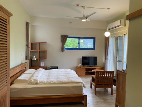a bedroom with a bed and a chair and a television at 飲山風民宿 in Jian