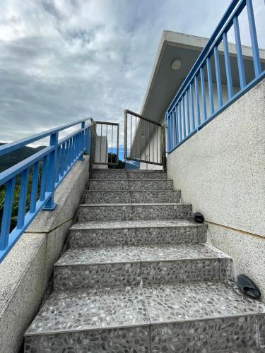 a staircase leading up to a building with blue railing at 飲山風民宿 in Jian