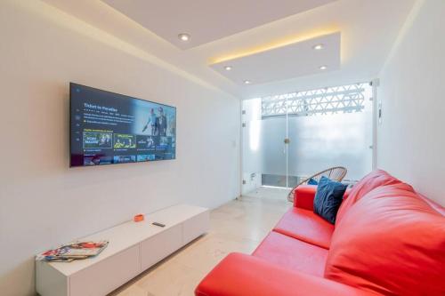 a living room with a red couch and a tv at LOFT ULTRA Moderno y Minimalista con 2 Camas KING Size in Durango