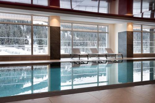 a swimming pool with tables and chairs in a building at Résidence Alhena in Flaine