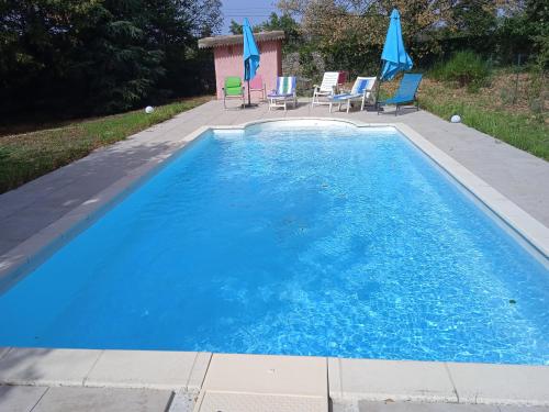 a large blue swimming pool with chairs and umbrellas at Maison calme avec piscine entourée de son parc in Quintenas