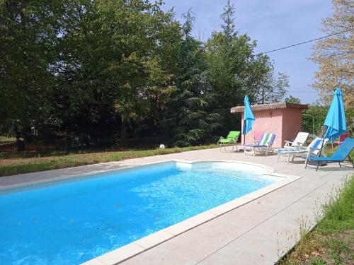 - une piscine avec 2 chaises longues et des parasols dans l'établissement Maison calme avec piscine entourée de son parc, à Quintenas