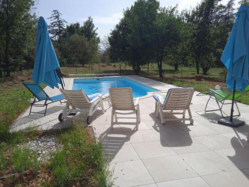 a group of chairs and umbrellas next to a pool at Maison calme avec piscine entourée de son parc in Quintenas