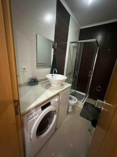 ein Badezimmer mit einem Waschbecken und einer Waschmaschine in der Unterkunft Appartement cosy et spacieux in Praia