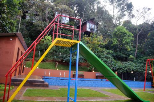 a playground with a slide in front of a pool at TREE6 WAYANAD in Vythiri