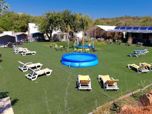 a group of lawn chairs and a blue pool at The Place in Albufeira