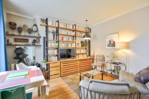 un salon avec une télévision et des étagères dans l'établissement L'Elégance à la Butte aux Cailles, à Paris