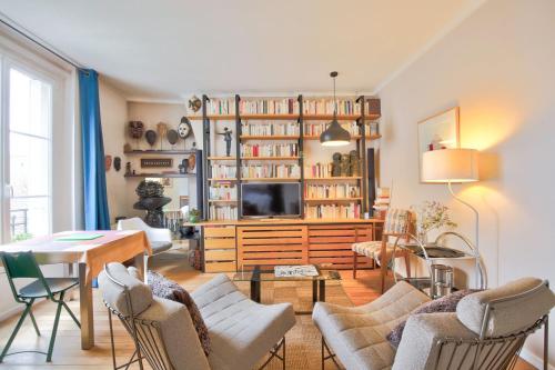 un salon avec une table, des chaises et une télévision dans l'établissement L'Elégance à la Butte aux Cailles, à Paris