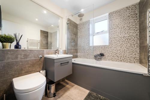 La salle de bains est pourvue de toilettes, d'une baignoire et d'un lavabo. dans l'établissement Stunning Abode in London - Private Garden, à Londres