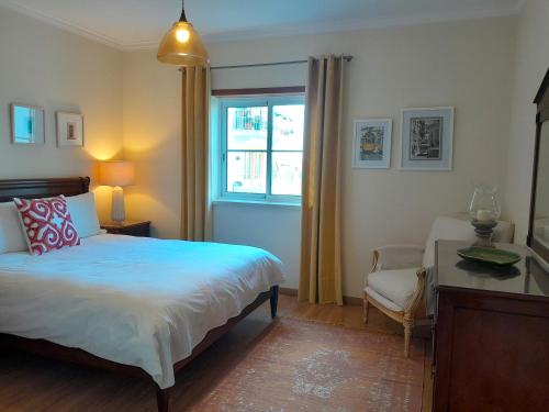 Schlafzimmer mit einem Bett, einem Schreibtisch und einem Fenster in der Unterkunft Palmeiras Apartement - T1 com Piscina in Baleal