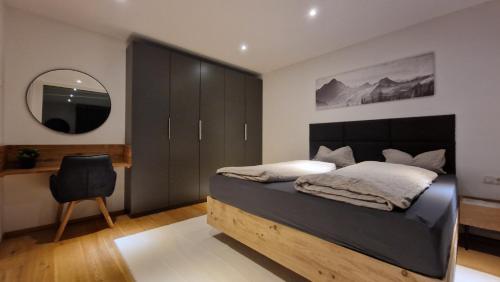 a bedroom with a bed and a mirror and a chair at Gartenwohnung mit Alpenblick in Fritzens
