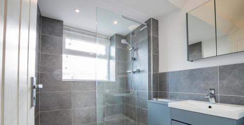 een badkamer met een douche, een wastafel en een spiegel bij Newly refurbished apartment in city centre in Hereford