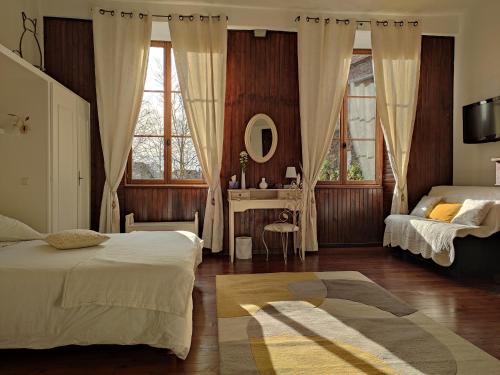 een slaapkamer met 2 bedden en een tafel met een spiegel bij B&B Amphitryon in Oloron-Sainte-Marie