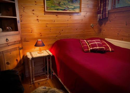 a bedroom with a red bed and a lamp on a table at Beautiful Cottage in Hveragerdi in Hveragerði