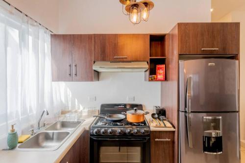 a kitchen with a stove and a stainless steel refrigerator at Elegante Condo CentroHistórico con Cochera in Durango