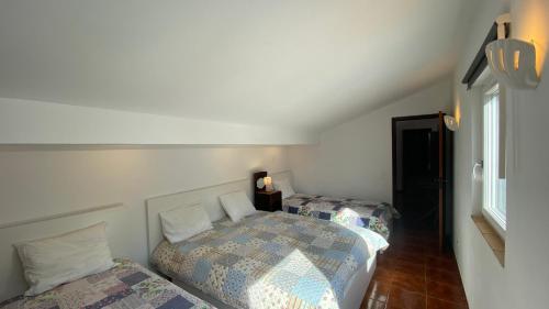 a bedroom with two beds and a window at Apartamento Miradouro in Carrapateira