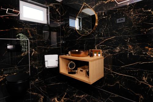 uma casa de banho com paredes em mármore preto e um espelho. em Villa Paula em Pula