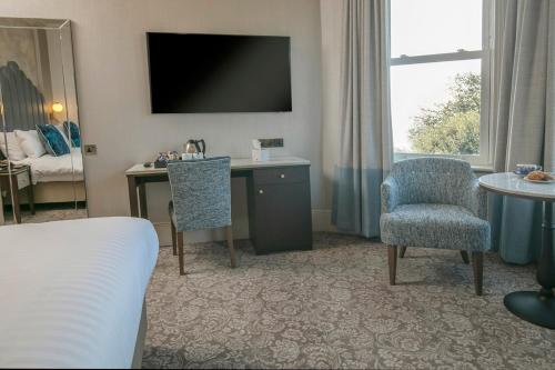a hotel room with a bed and a desk and a chair at voco The Clifton Folkestone by IHG in Folkestone