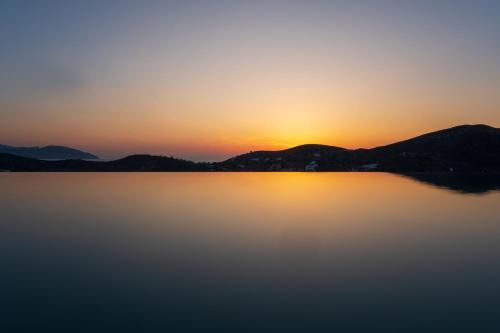 a sunset over a lake with mountains in the background at Villa Mirabilis in Ios Chora