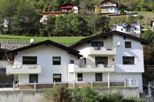 a white building with a black roof at Ferienwohnung Raich in Wenns