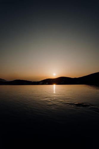 a sunset over a lake with the sun setting at Villa Mirabilis in Ios Chora