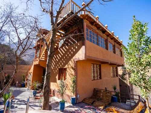 una casa grande con un árbol delante en Riad Atlas Bangalo en Imlil