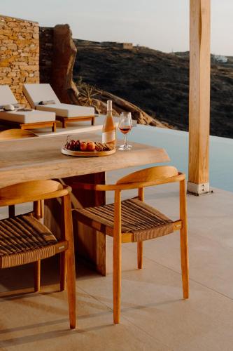 a wooden table with a plate of fruit and wine glasses at Villa Mirabilis in Ios Chora