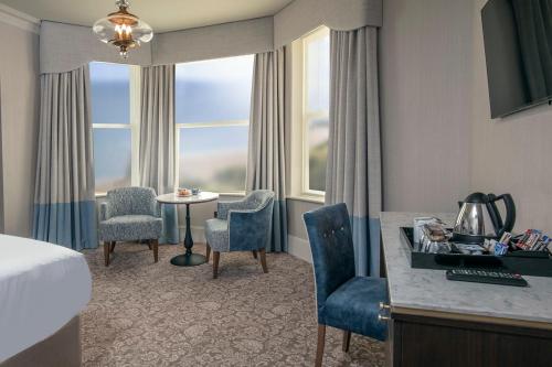 a hotel room with a bed and a table and chairs at voco The Clifton Folkestone by IHG in Folkestone