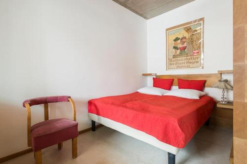 una camera con letto rosso e sedia di Dichterstube im Living Kampill a Bolzano