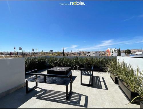 a patio with a table and a bench on a roof at Maravilloso Departamento in Chihuahua
