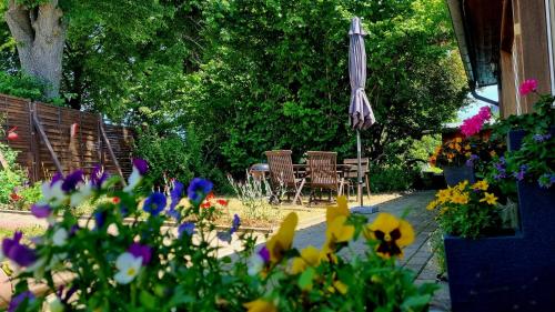 un jardín con sombrilla, sillas y flores en Urlaubsmagie - Wohnung mit Grill, Terrasse & Pool -W5, en Lichtenhain