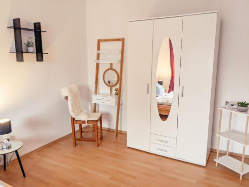 a white cabinet with a mirror and a chair in a room at W5 - Urlaubsmagie - Wohnung mit Grill, Terrasse & Pool in Lichtenhain