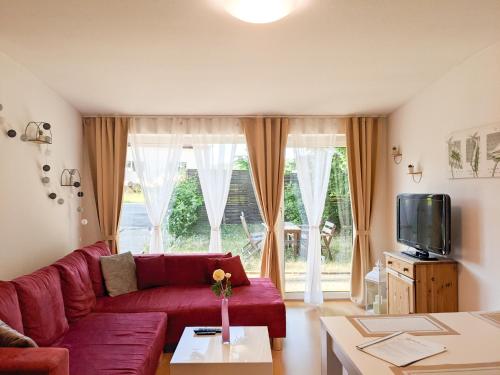 a living room with a red couch and a large window at W5 - Urlaubsmagie - Wohnung mit Grill, Terrasse & Pool in Lichtenhain