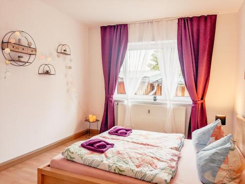 a bedroom with a bed and a window with purple curtains at W5 - Urlaubsmagie - Wohnung mit Grill, Terrasse & Pool in Lichtenhain