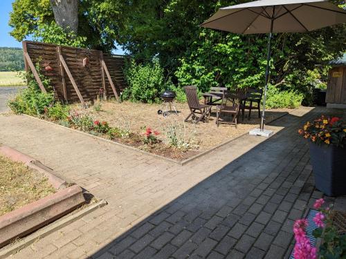 a patio with an umbrella and a table and chairs at W5 - Urlaubsmagie - Wohnung mit Grill, Terrasse & Pool in Lichtenhain