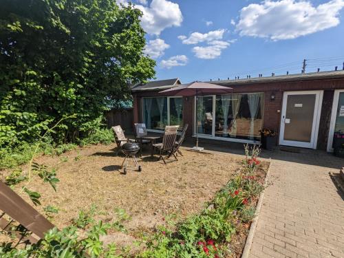 a patio with a table and chairs and an umbrella at W5 - Urlaubsmagie - Wohnung mit Grill, Terrasse & Pool in Lichtenhain
