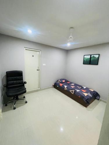 a bedroom with a bed and a chair in it at vaishnav cottage in Agartala