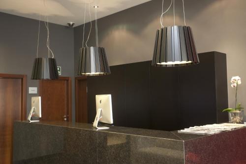 a lobby with a counter with three hanging lights at Hotel Carris Marineda in A Coruña