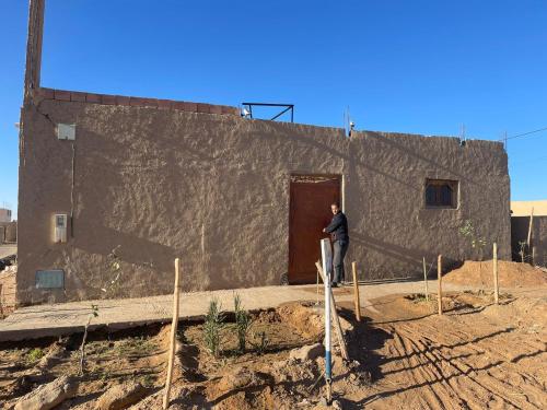 a man standing in front of a building at GITE Take your time in Merzouga