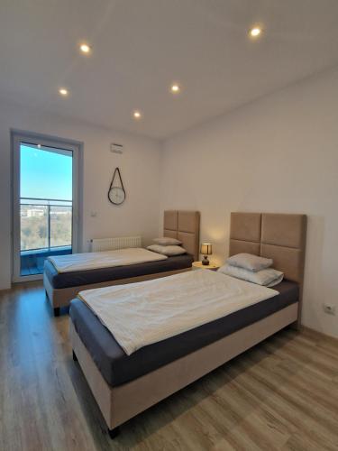 2 Betten in einem Zimmer mit einem großen Fenster in der Unterkunft Szklane Tarasy Premium Two Bedrooms FAKTURA FAST CHECK-IN in Rzeszów