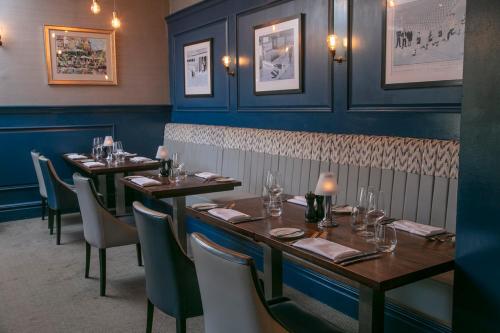 a dining room with tables and chairs and blue walls at voco The Clifton Folkestone by IHG in Folkestone