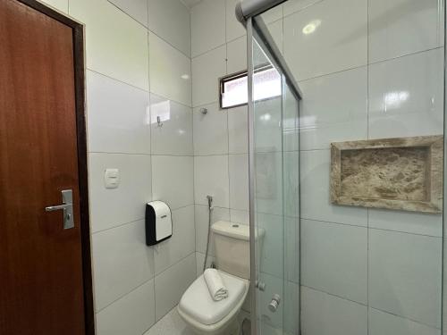 a bathroom with a toilet and a glass shower at Hotel Aconchego do Velho Chico in Piranhas