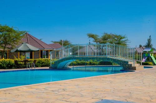a bridge over a swimming pool with a playground at Calfie Resort Kisumu in Ahero